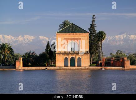 Morocco, Marrakesh, Menara Pavilion reflected on its lake in the late afternoon sunshine. Snow covered Atlas Mountains in the background. Stock Photo