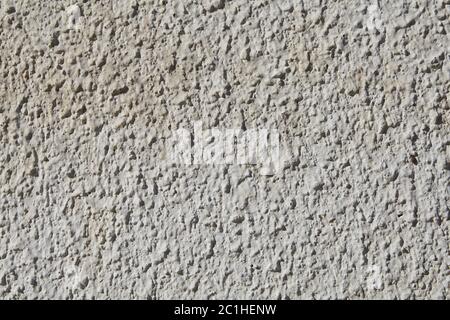 The texture of the coarse grained stucco is off-white in color on the exterior plastered wall. Stock Photo