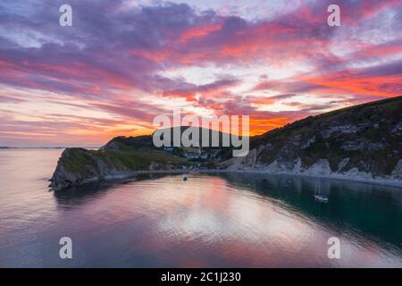 Lulworth Cove, Dorset, UK.  15th June 2020.  UK Weather. A dramatic sunset at Lulworth Cove in Dorset with the clouds turn red at the end of a warm sunny day.  Picture Credit: Graham Hunt/Alamy Live News Stock Photo