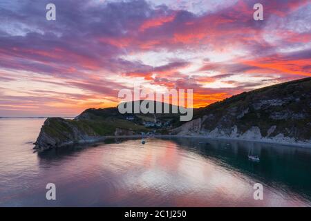 Lulworth Cove, Dorset, UK.  15th June 2020.  UK Weather. A dramatic sunset at Lulworth Cove in Dorset with the clouds turn red at the end of a warm sunny day.  Picture Credit: Graham Hunt/Alamy Live News Stock Photo