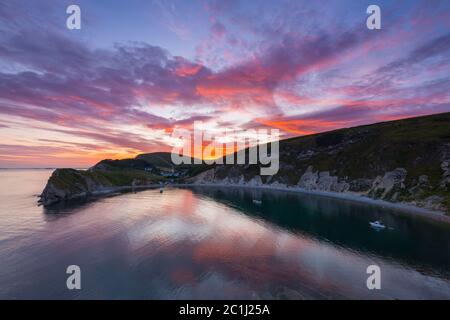 Lulworth Cove, Dorset, UK.  15th June 2020.  UK Weather. A dramatic sunset at Lulworth Cove in Dorset with the clouds turn red at the end of a warm sunny day.  Picture Credit: Graham Hunt/Alamy Live News Stock Photo