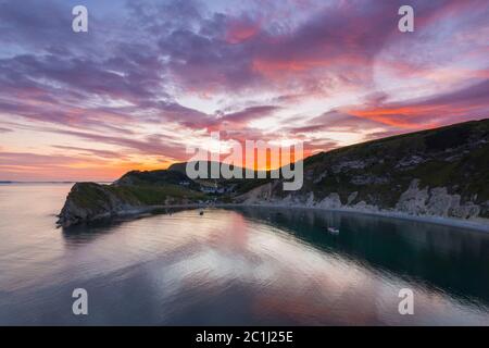 Lulworth Cove, Dorset, UK.  15th June 2020.  UK Weather. A dramatic sunset at Lulworth Cove in Dorset with the clouds turn red at the end of a warm sunny day.  Picture Credit: Graham Hunt/Alamy Live News Stock Photo