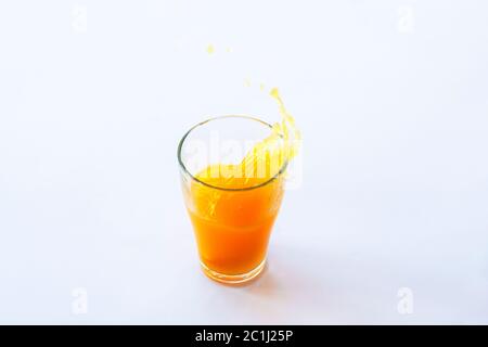 Glass of splashing healthy orange juice isolated on white background. Stock Photo