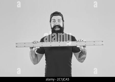 Perfect size. Bearded man with big measuring instrument. Measuring with ruler. Size measurement. Measuring length. Size clothes. Student study stem disciplines. Ruler tool equipment. Shop assistant. Stock Photo