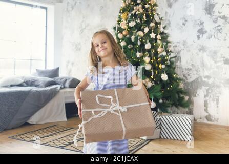 Adorable little girl with Christmas present by the Christmas tree Stock Photo
