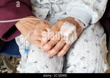 Close up of elderly woman hands with intravenous drip on a wheelchair Stock Photo