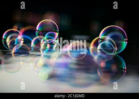 background with many sparkling iridescent soap bubbles float on the water and are reflected in the rays of the sunset Stock Photo