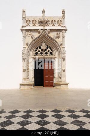 Portugal Tomar. Portal of the Church of Saint John the Baptist, built between 15th and 16th Centuries. Typical black and white cobblestones foreground Stock Photo