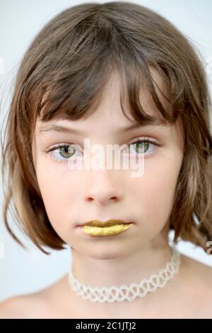 Is silence golden? Portrait of a child with sealed golden lips and intense stare. Stock Photo