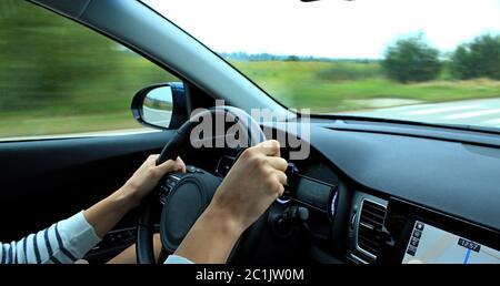 Wrong position of manâ€™s hands on the steering wheel inside fast moving vehicle Stock Photo