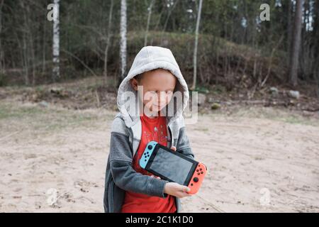 young boy holding a Nintendo games console sharing the screen Stock Photo