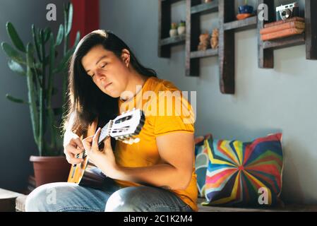 side view, man with long hair playing acoustic guitar relaxed attitude Stock Photo