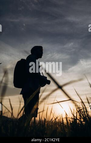Photographer standing on hill with background of sunset Stock Photo