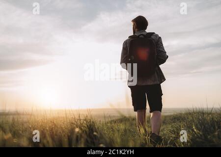 Back view of photographer walking on high hill with backpack Stock Photo