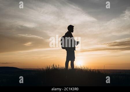 Silhouette of photographer standing on hill during sunset Stock Photo