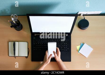 Unrecognizable woman writes on her smartphone at a desk in her home Stock Photo