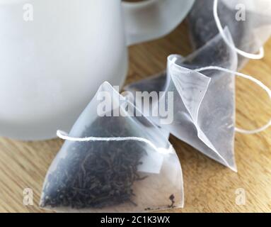 bags of elite tea in silk fabric packing and tea mug on a wooden background Stock Photo