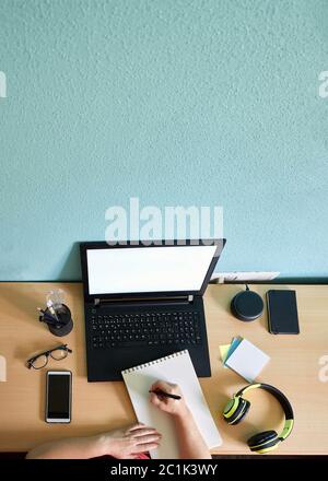 Unrecognizable woman writes on her notebook on a desk in her home Stock Photo