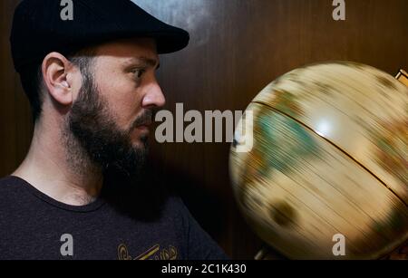 bearded man watching globe spinning Stock Photo