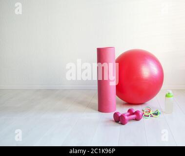 Gym ball, yoga mat, skipping rope, dumbbell  and bottle of the water closeup on white background Stock Photo