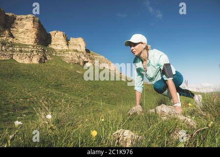 Athletic woman was ready to run at the foot of the rocks. Fitness runner in the finished starting line creates an outdoor summer Stock Photo