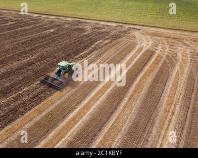 An endless agricultural field after harvesting with tractor on it . Cultivation of the soil by a tractor for sowing works. Stock Photo