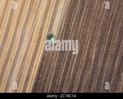 Agricultural field after harvesting and part of the field plowed of tractor under sowing works . Stock Photo
