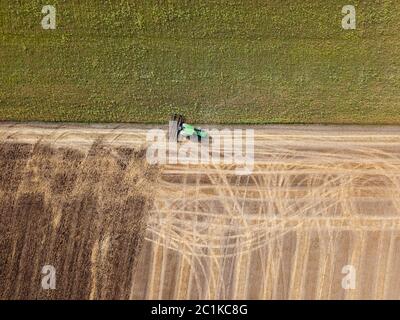 Panoramic view of tractor plowing the soil after harvesting on the field. Top view from drone. Stock Photo