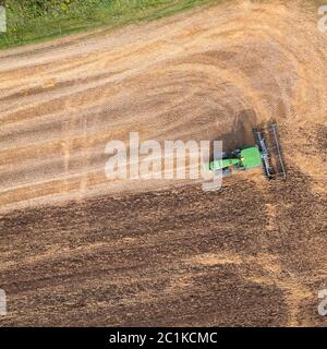 The tractor plows the field, preparing the soil for agricultural work. Top view. Stock Photo