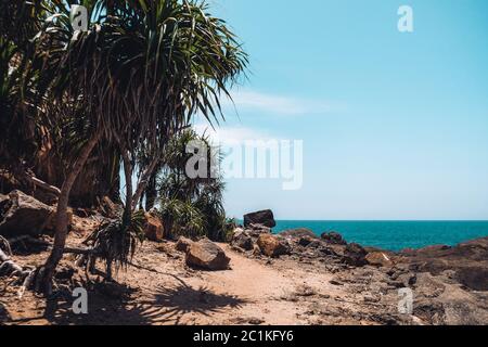 Wonderful view from the secluded tropical beach in Sri Lanka. Unknown destination with nobody around. Isolated spot with trees, rocks and ocean Stock Photo