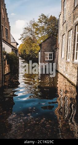 Outdoor scenic landscape from Bruges, Belgium. Beautiful reflection in the water of river in the city center of Brugge. Brick buildings and moody view Stock Photo