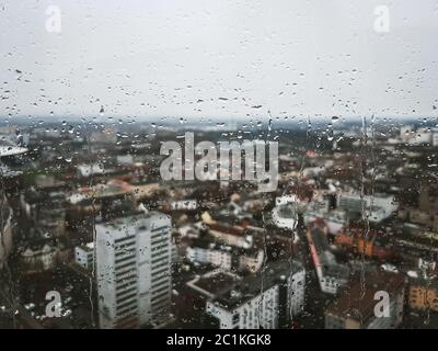 Rain drops running down the glass window overlooking the whole city Cologne in Germany. Cityscape view from the top viewpoint in the city centre. Stock Photo