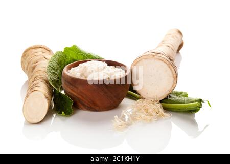 Fresh and grated horseradish in wooden bowl. Stock Photo