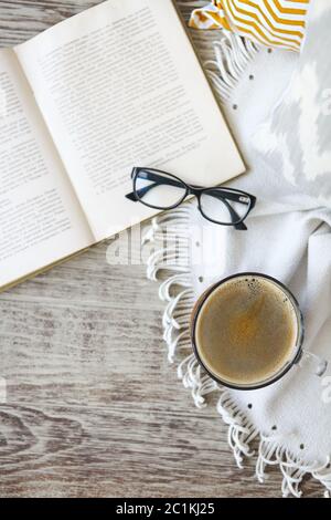Cup of coffee staying by the book and glases on the wooden table Stock Photo