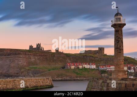 Whitby, Uk - Mar 2020: Golden Hour skies over Whitby Abbey and the pier at Whitby Bay Stock Photo