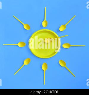 A yellow plastic plate and spoons lay around it on a bright blue background. The concept of a holiday, picnic. Stock Photo