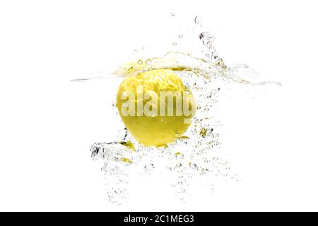 one yellow apple falling into water on a white background with splashes, drops and bubbles. Stock Photo