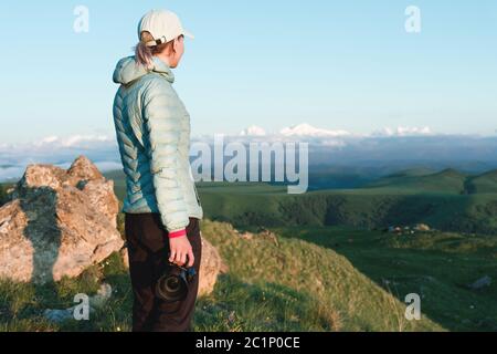 Portrait of a girl photographer in a cap in nature with a camera in hand. Back view Stock Photo