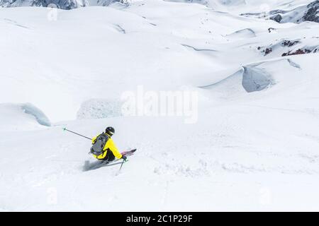 A skier at speed rides on a snowy slope freeride. The concept of winter extreme sports Stock Photo