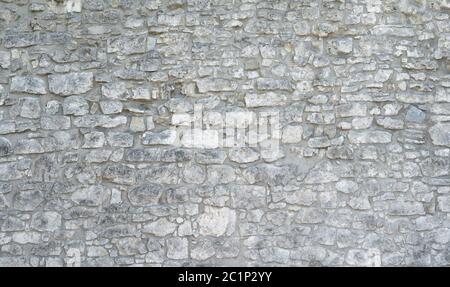 Very old stone wall made of many gray coarse natural stones Stock Photo