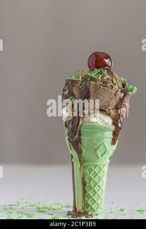 Icecream cone with green wafer and chocolate ice cream with cherry on top Stock Photo