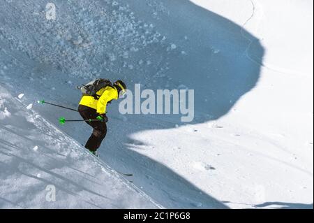 A skier at speed rides on a snowy slope freeride. The concept of winter extreme sports