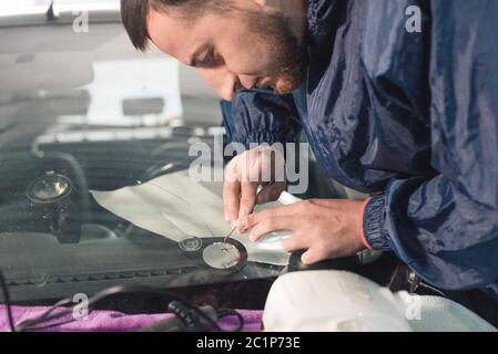 Close up Automobile glazier worker fixing and repair windscreen or windshield of a car in auto service station garage Stock Photo