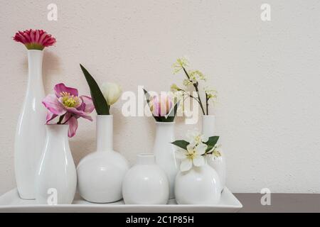 different pink flowers in vases on white background Stock Photo