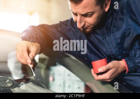 Close up Automobile glazier worker fixing and repair windscreen or windshield of a car in auto service station garage Stock Photo