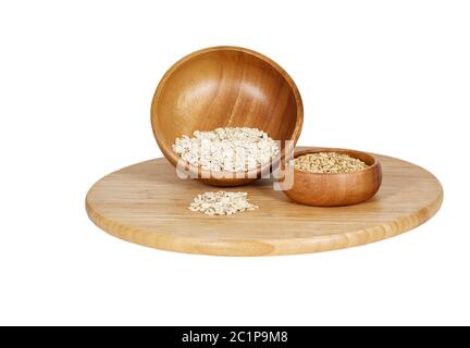 Rolled Oats with oat groats in wooden bowls on a bamboo cutting board isolated on white Stock Photo