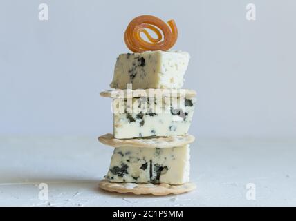 Blue cheese cubes on crackers stack close up side view photo on textured background Stock Photo