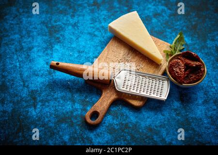 Grated parmesan cheese and metal classic grater placed on wooden cutting board Stock Photo