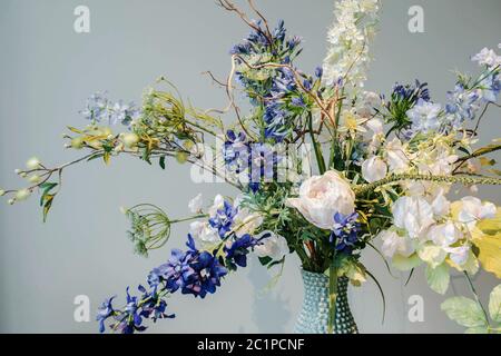 Colorful Fake flowers in a vase on the table colorful green and blue background texture,modern design Stock Photo