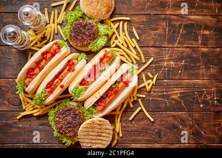 Fastfood assortment. Hamburgers and hot dogs placed on rusty wood table Stock Photo